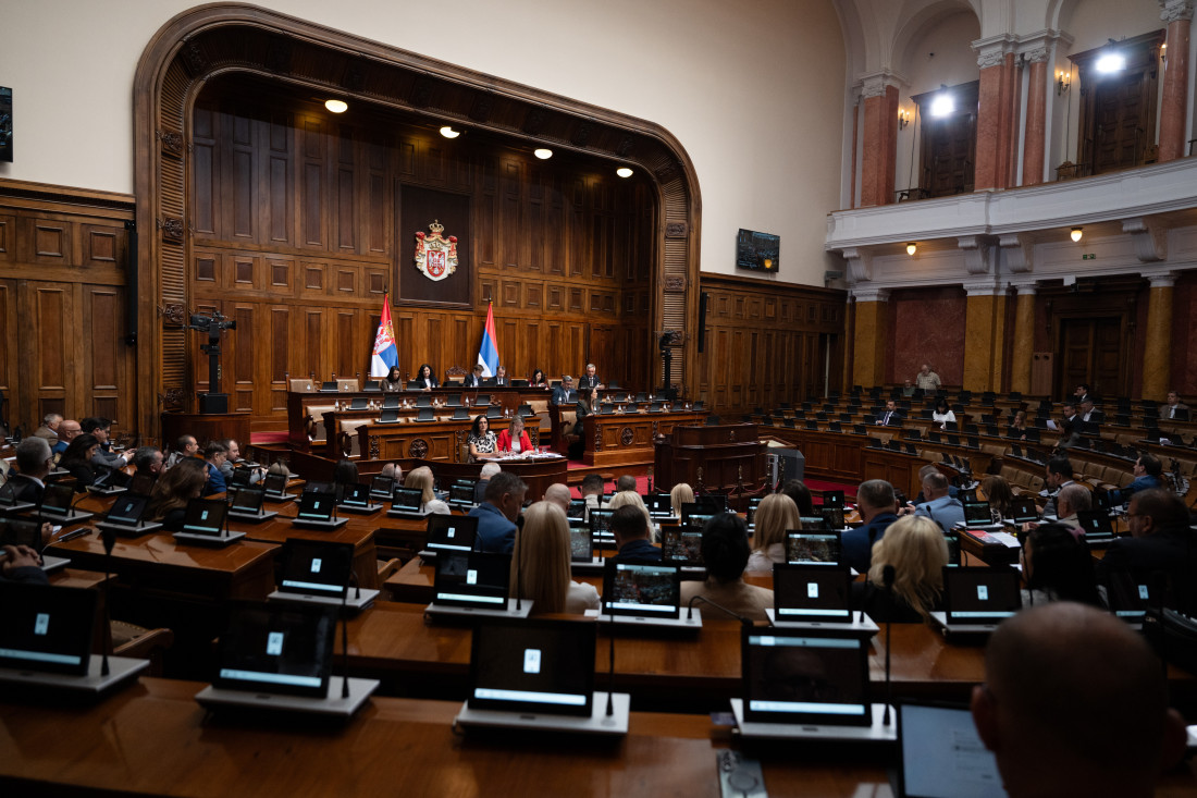 Široki kadar velike sale Narodne skupštine sa poslanicima u klupama, u pozadini grb Srbije i dve zastave