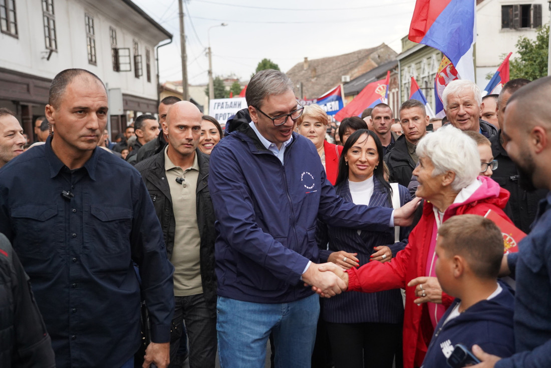 Predsednik Aleksandar Vučić se rukuje sa građankom među okupljenima sa srpskim zastavama
