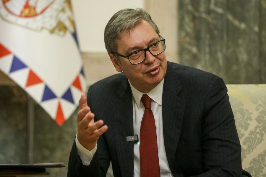 Predsednik Srbije Aleksandar Vučić gestikulira tokom obraćanja, u pozadini zastava Srbije