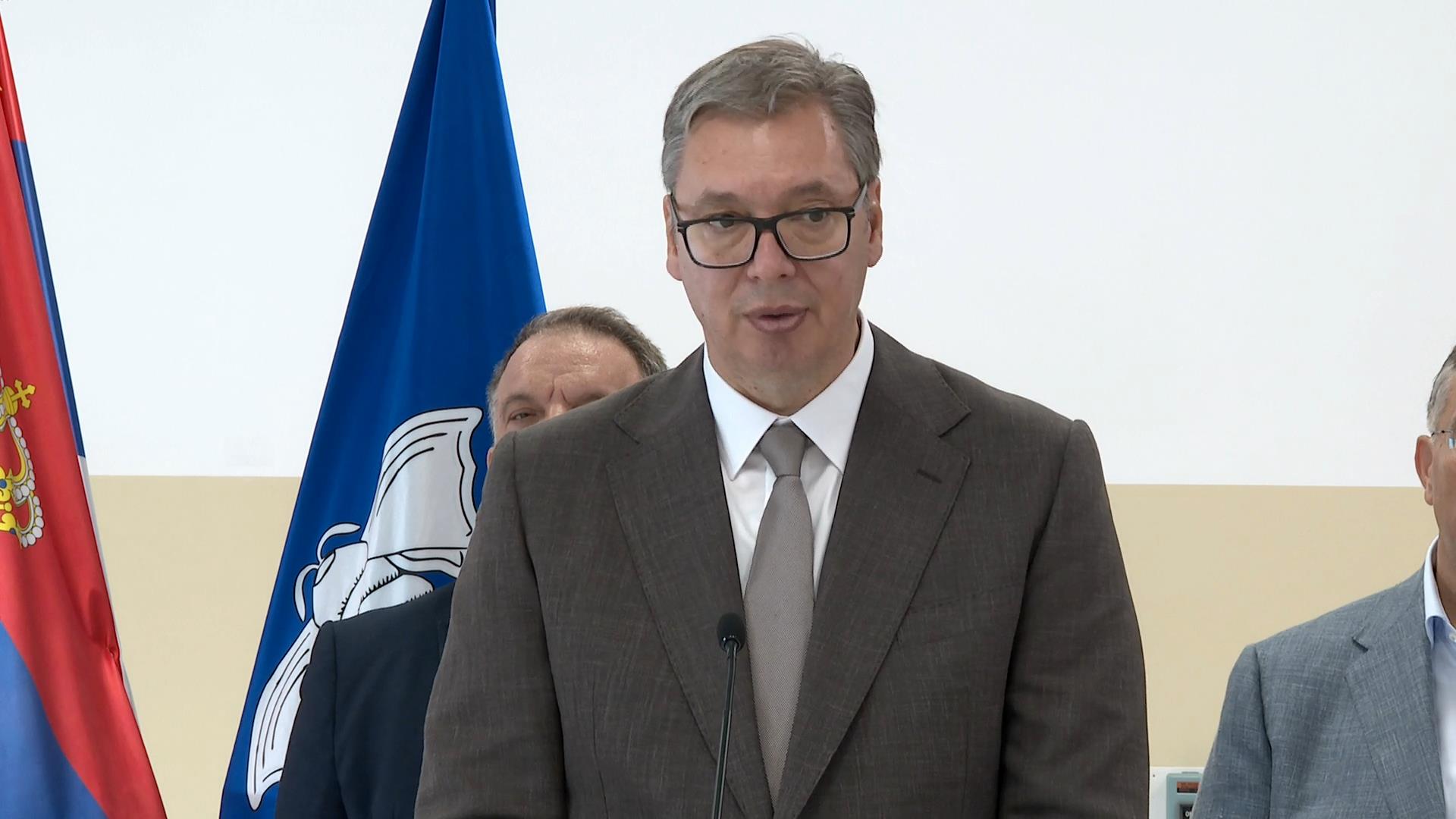 Aleksandar Vučić govori za mikrofonom ispred zastave Srbije