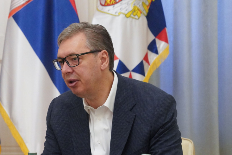 Aleksandar Vučić sedi ispred srpskih zastava tokom sastanka