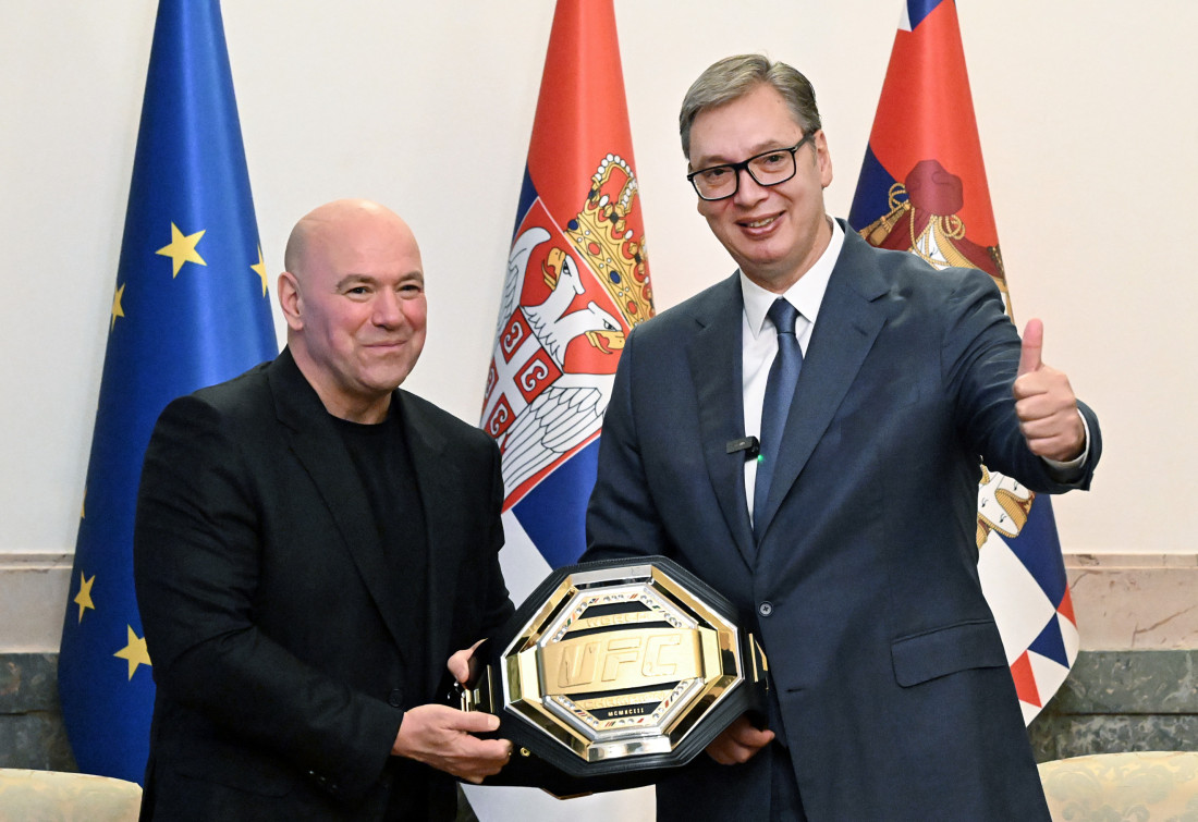 Dejna Vajt i Aleksandar Vučić drže zlatni UFC šampionski pojas, u pozadini zastave Srbije i Evropske unije