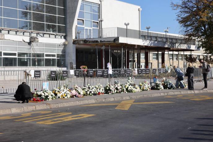 Cveće i sveće ispred Železničke stanice u Novom Sadu, sa oštećenim delom nadstrešnice i tablama sa imenima na ogradi