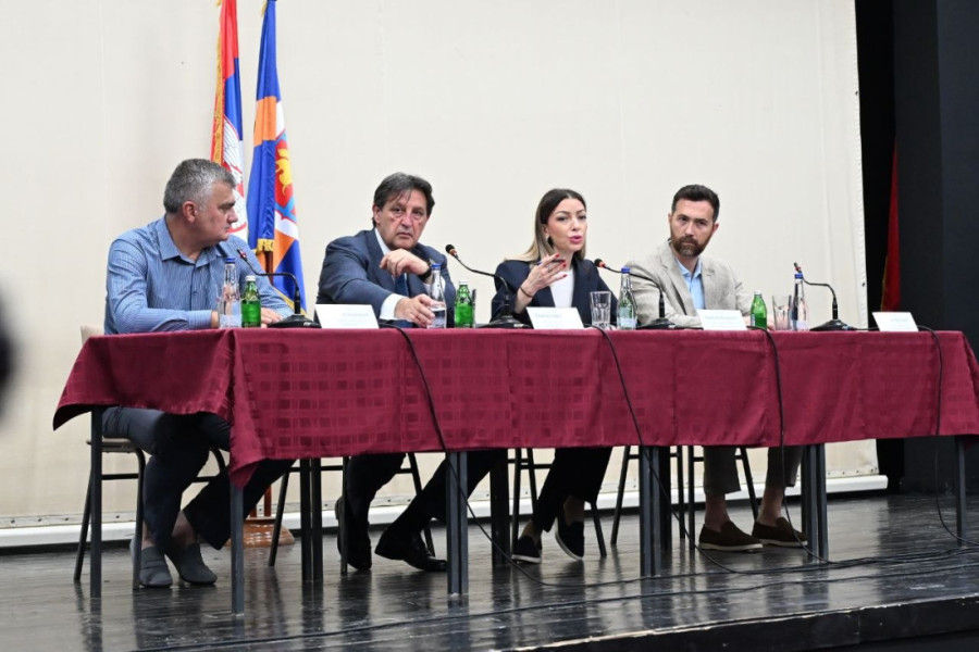 Četiri učesnika skupa sede za stolom na bini ispred zastave Srbije