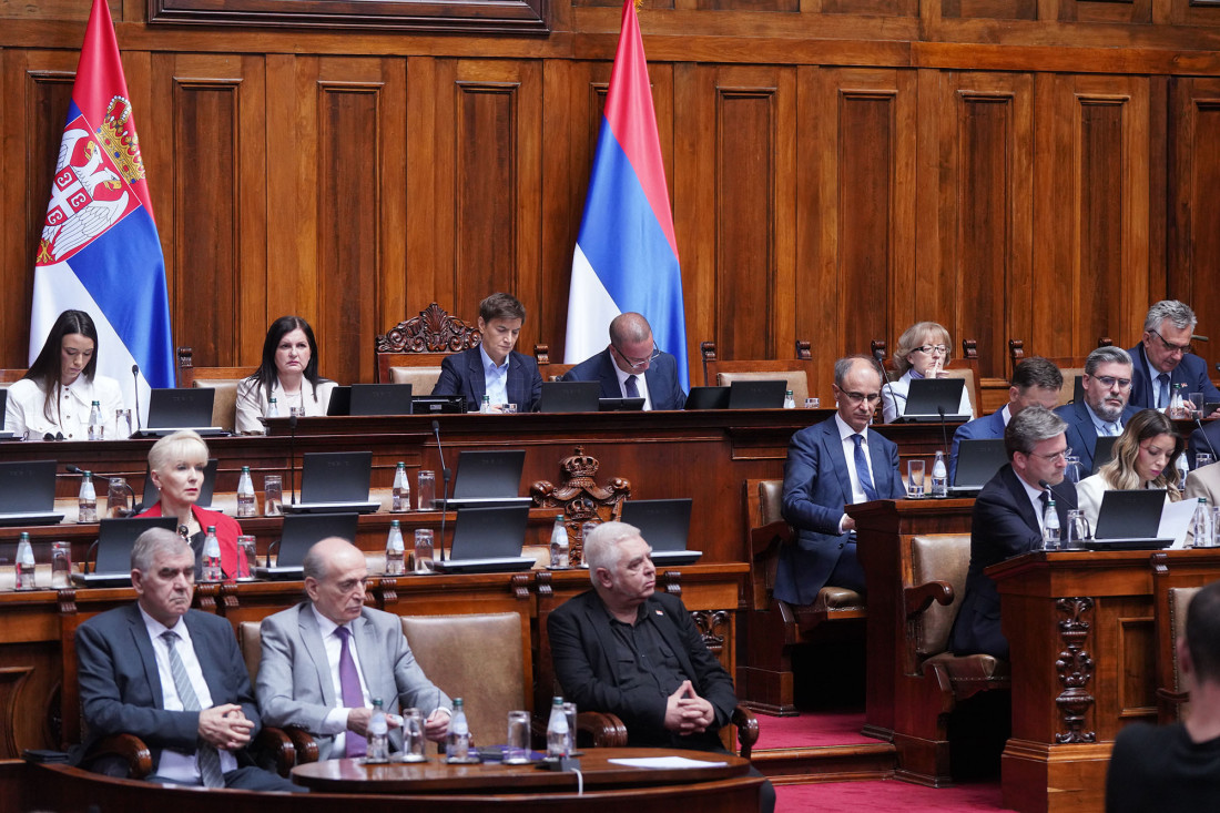 Poslanici i članovi Vlade u sali Narodne skupštine, u pozadini dve zastave Srbije i drvena oplata