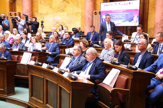 Učesnici konferencije u sali Skupštine Srbije, govornik za govornicom i banner skupa u pozadini