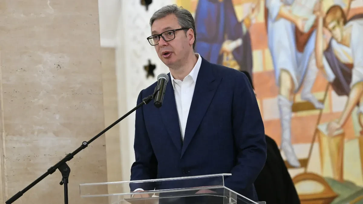 Aleksandar Vučić govori za providnom govornicom uz mikrofon, u pozadini zidna freska