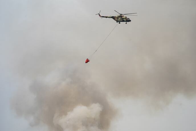 Helikopter sa vedrom za vodu iznad gustog dima tokom gašenja požara