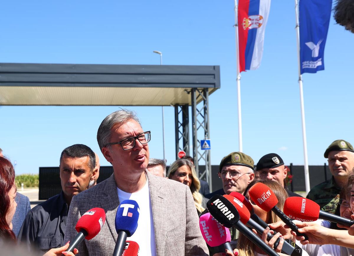 Aleksandar Vučić govori novinarima ispred fabrike, oko njega mikrofoni i pripadnici vojske