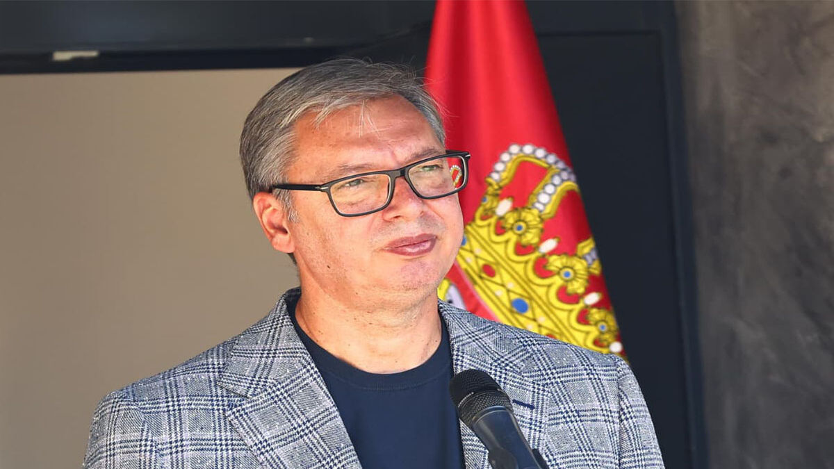 Aleksandar Vučić govori za mikrofonom ispred zastave Srbije