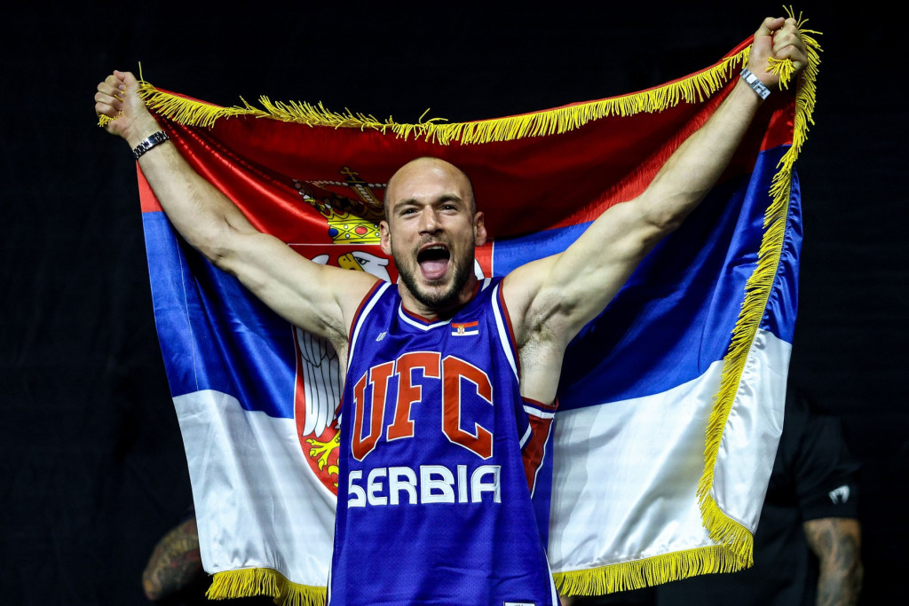 Borac u dresu sa natpisom UFC Serbia podignutih ruku drži zastavu Srbije iznad glave