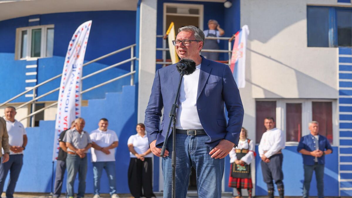Aleksandar Vučić govori za mikrofonom ispred plavo-bele zgrade, okupljeni građani u pozadini
