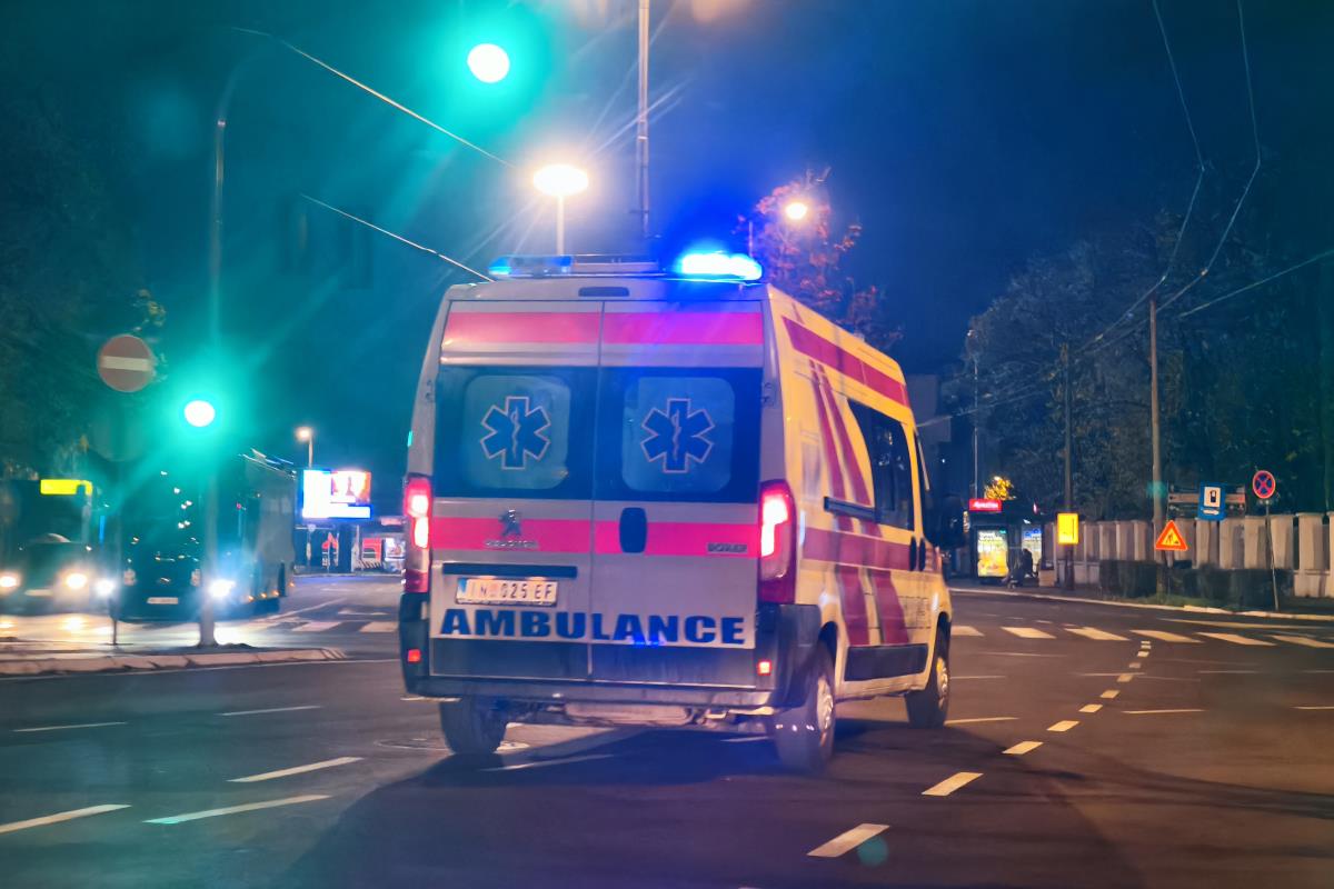 Vozilo Hitne pomoći sa upaljenom plavom rotacijom na raskrsnici u noćnoj vožnji