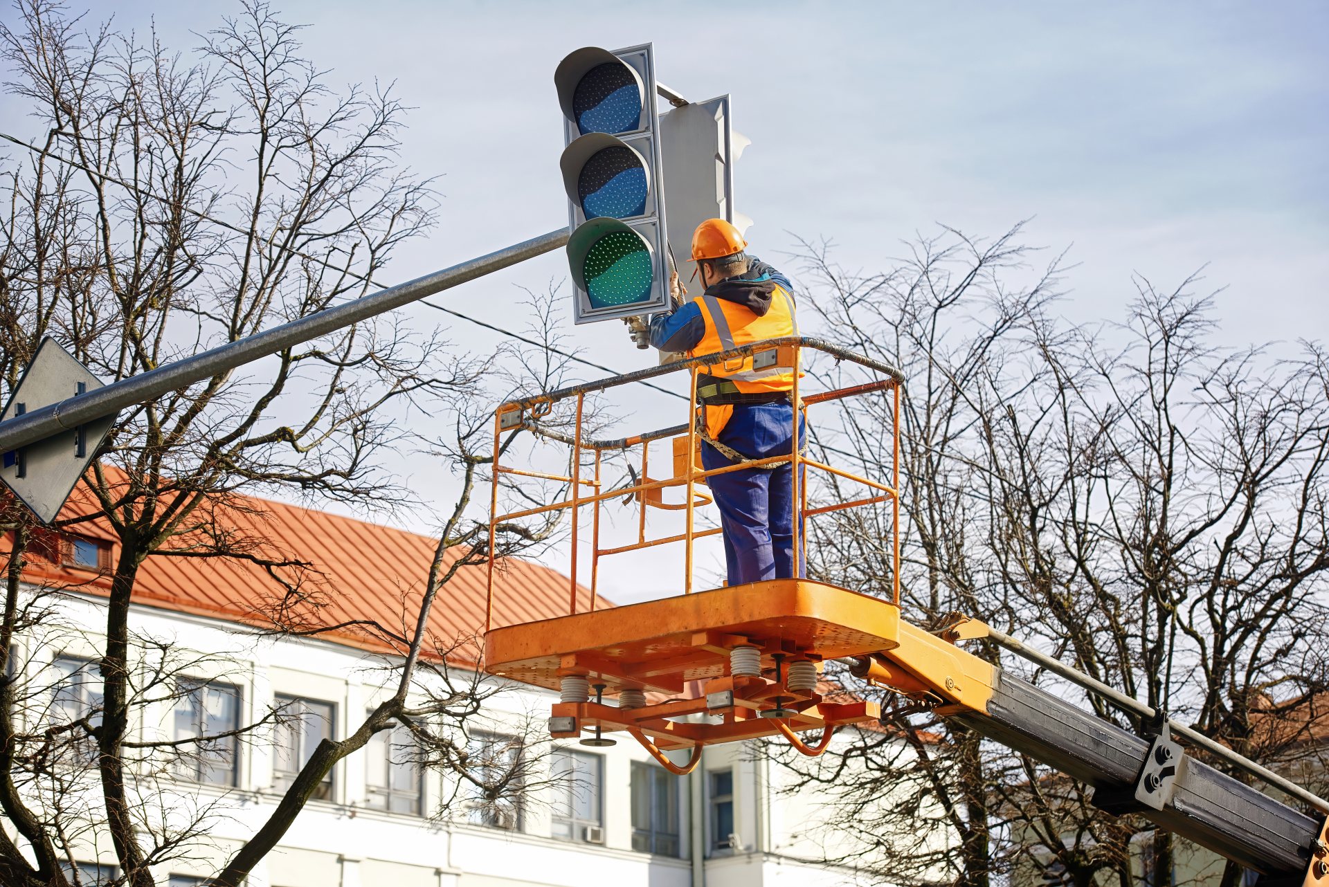 Radnik u korpi dizalice postavlja semafor iznad ulice