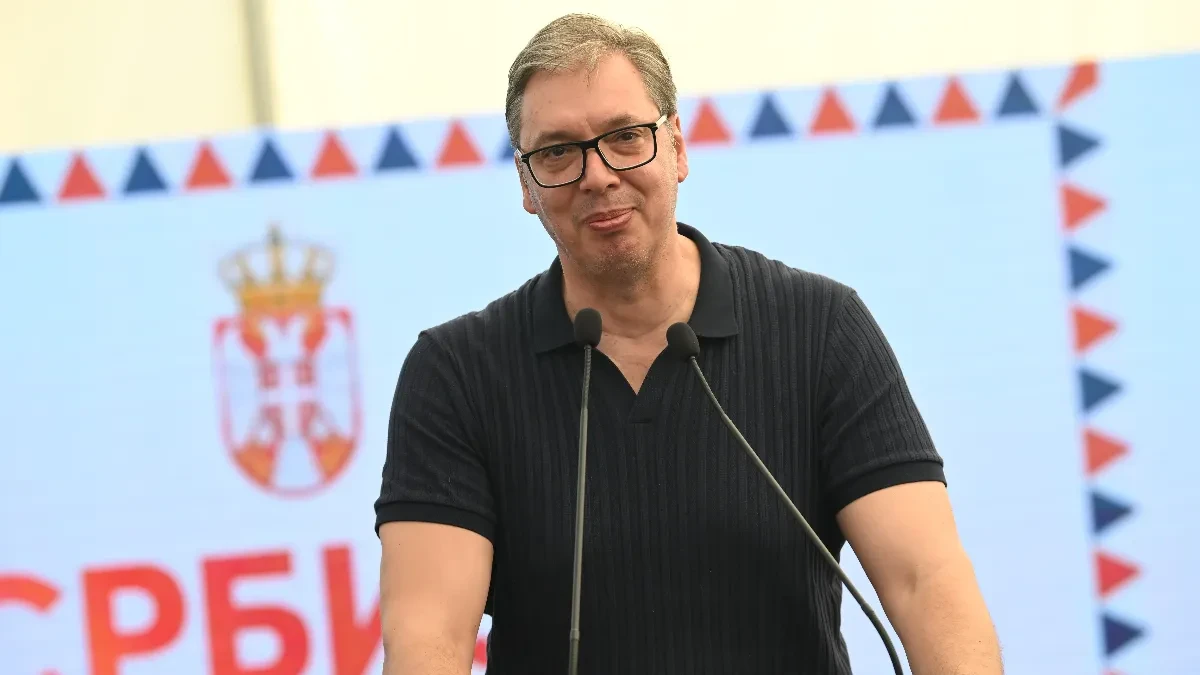 Aleksandar Vučić za mikrofonom ispred plave pozadine sa grbom Srbije