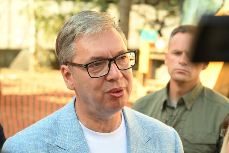 Predsednik Aleksandar Vučić govori novinarima na otvorenom, iza njega stoji muškarac u maslinastoj jakni