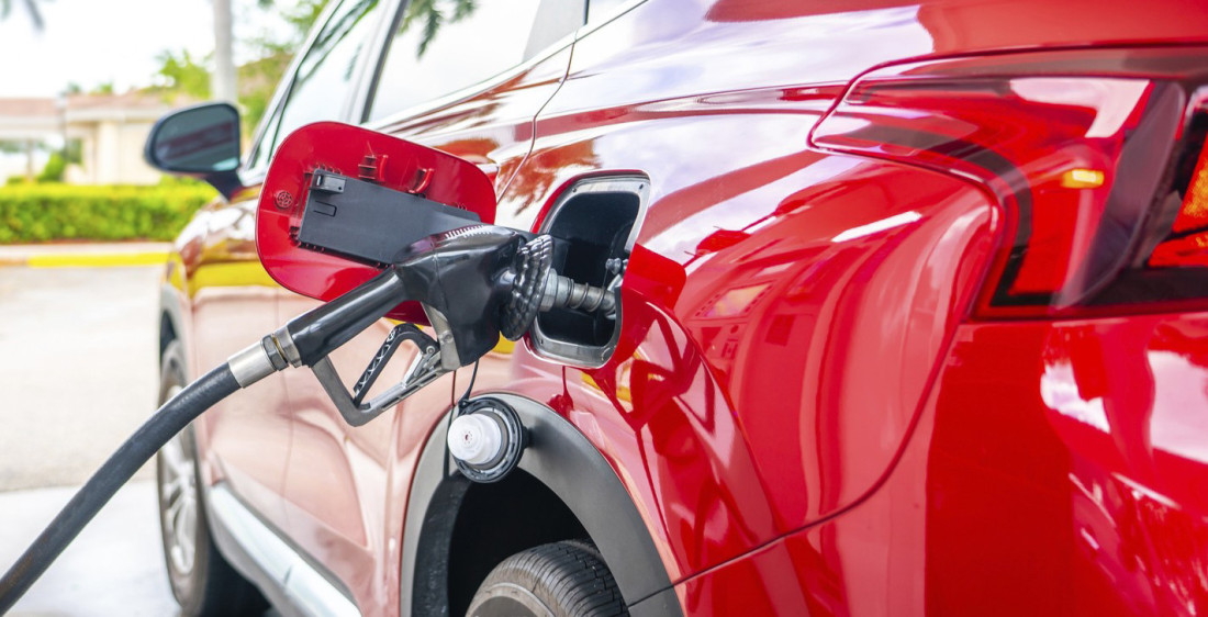 Točenje goriva na benzinskoj pumpi, pištolj u rezervoaru crvenog automobila