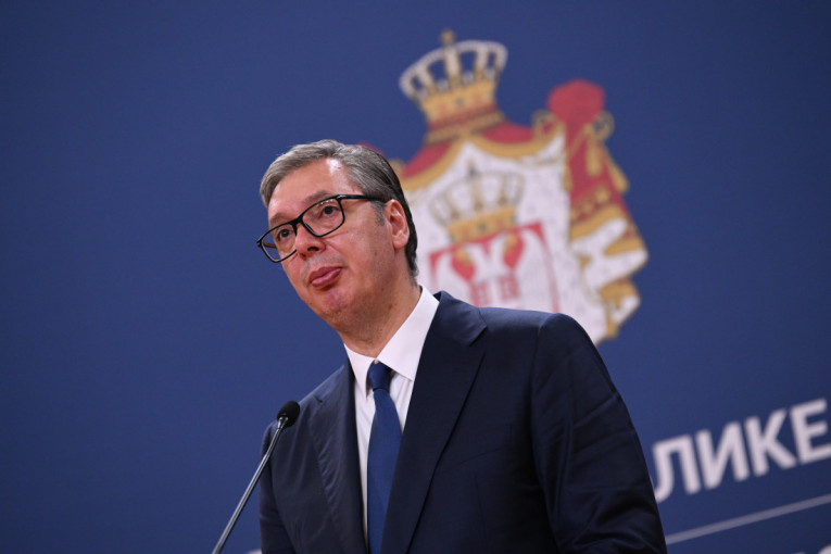 Aleksandar Vučić za govornicom ispred plave pozadine sa grbom Srbije