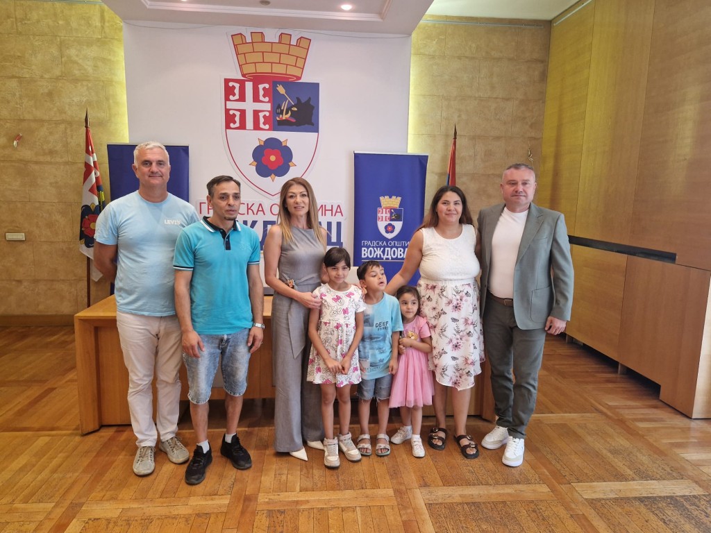 Porodica Vučković sa troje dece i predstavnici opštine Voždovac u Svečanoj sali, ispred grba opštine
