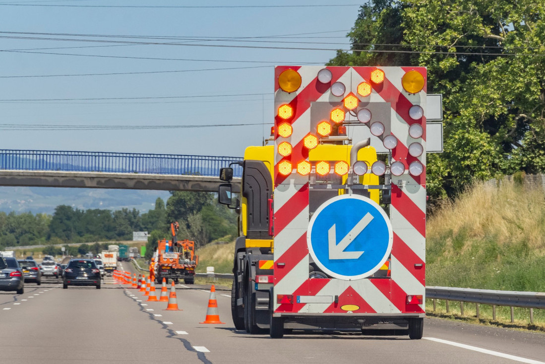 Kamion sa svetlosnom signalizacijom i saobraćajni čunjevi na traci auto-puta tokom radova