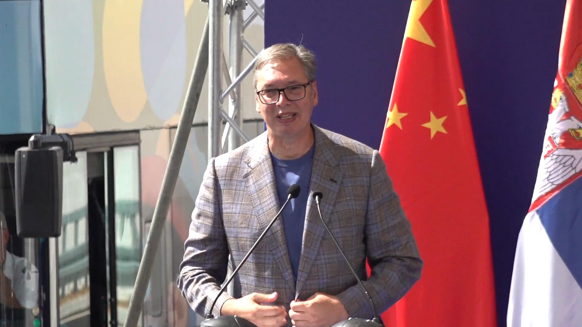 Aleksandar Vučić govori za govornicom, iza njega zastave Kine i Srbije