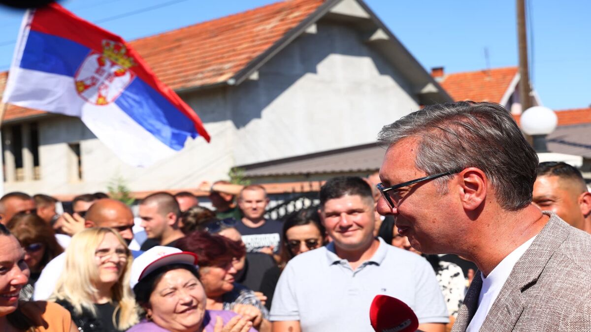 Aleksandar Vučić razgovara sa okupljenim građanima, u pozadini srpska zastava