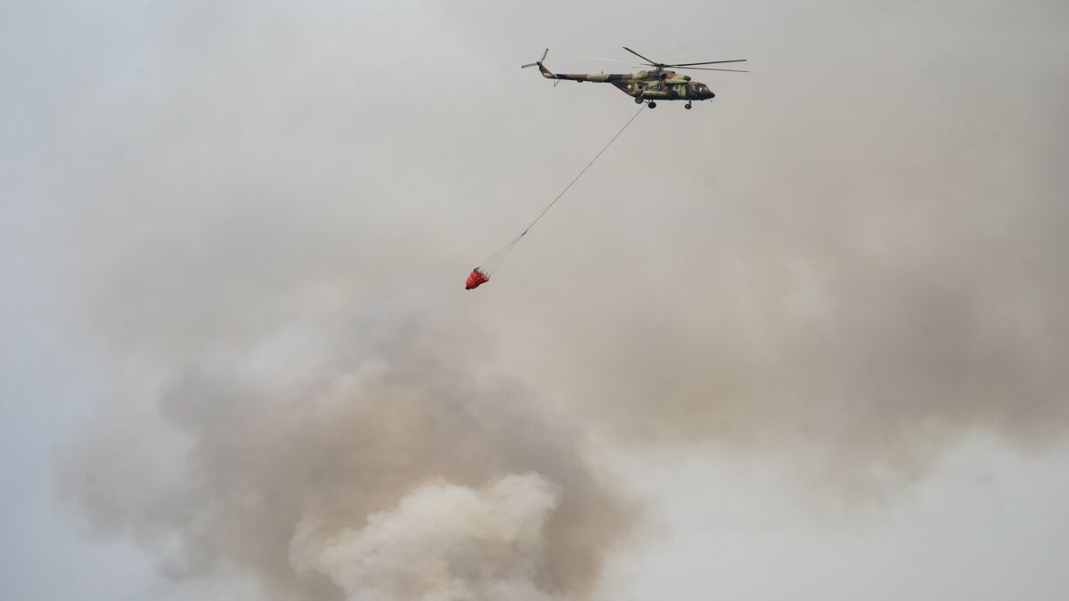 Helikopter sa kofom za vodu iznad gustog dima požara
