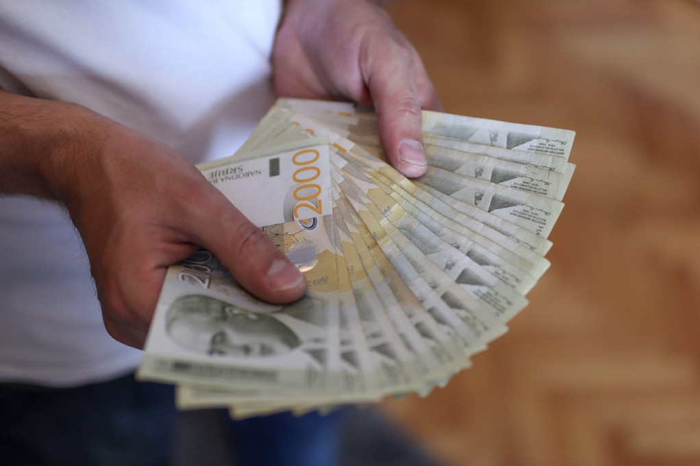 Ruke drže lepezu novčanica od 2.000 dinara