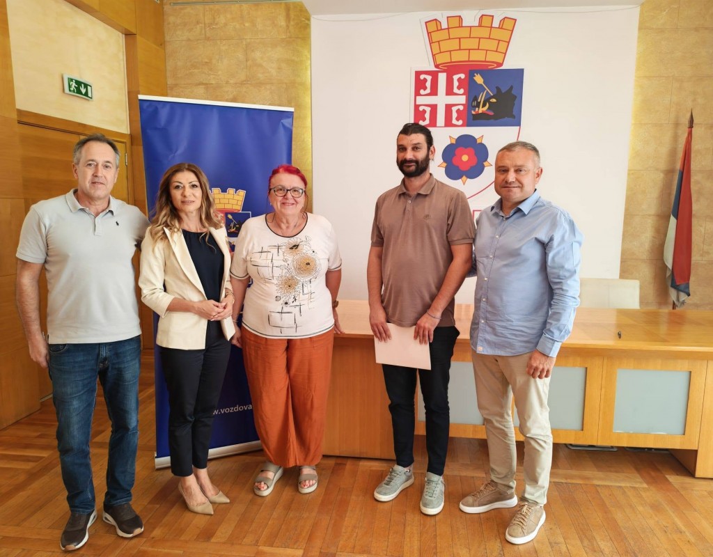 Uručenje ugovora porodici Ničić u sali opštine Voždovac, pet osoba ispred grba opštine
