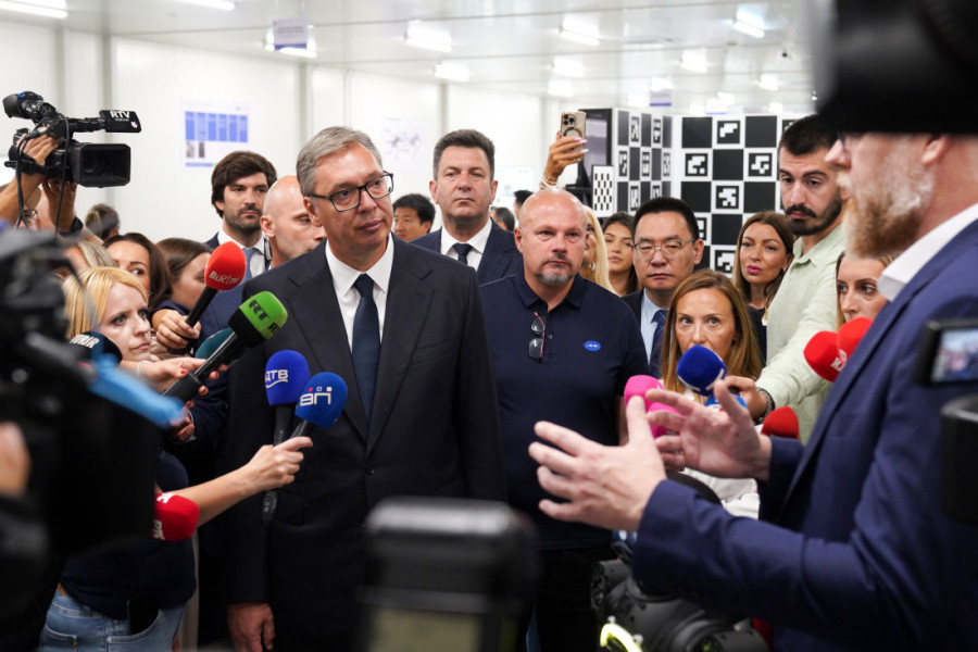 Aleksandar Vučić okružen novinarima sa mikrofonima tokom obilaska fabrike robota u Šapcu