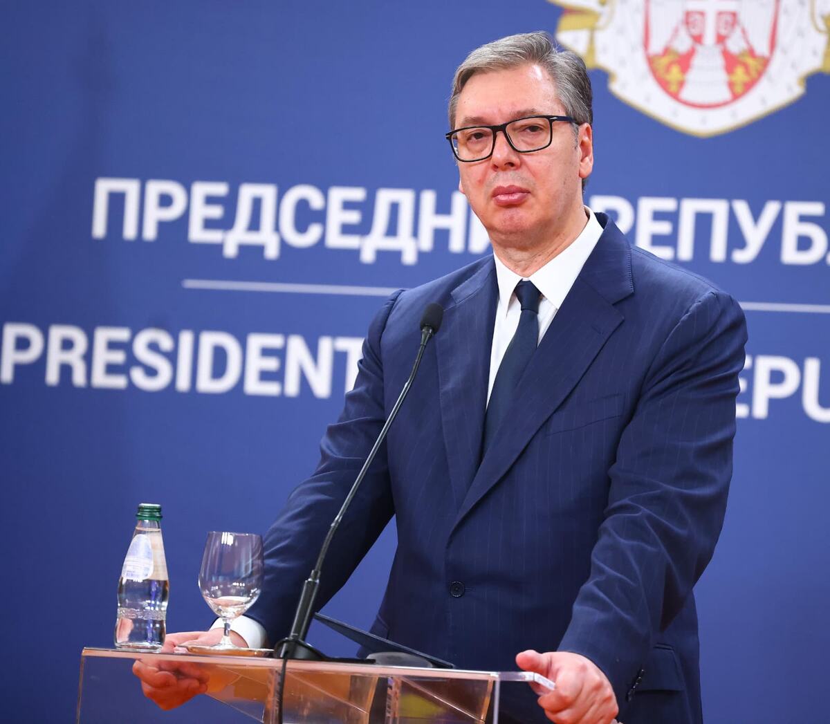 Aleksandar Vučić govori za govornicom ispred plave table sa natpisom Predsednik Republike