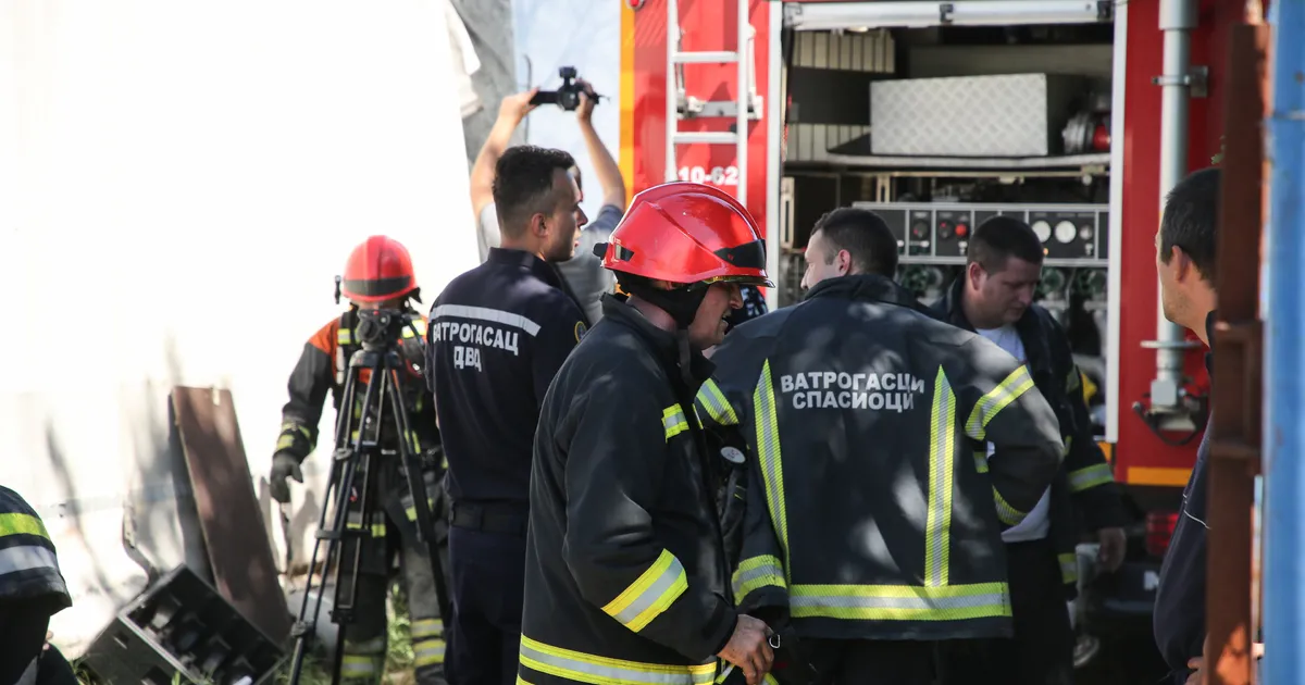 Vatrogasci u zaštitnoj opremi pored vatrogasnog vozila na mestu intervencije