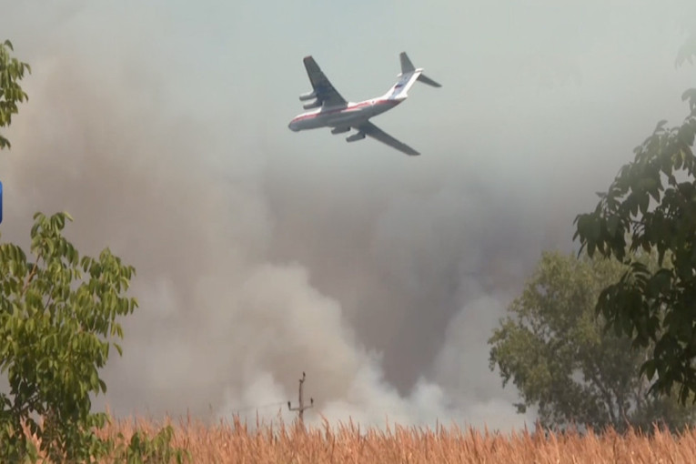 Protivpožarni avion Iljušin leti iznad gustog dima nad poljem