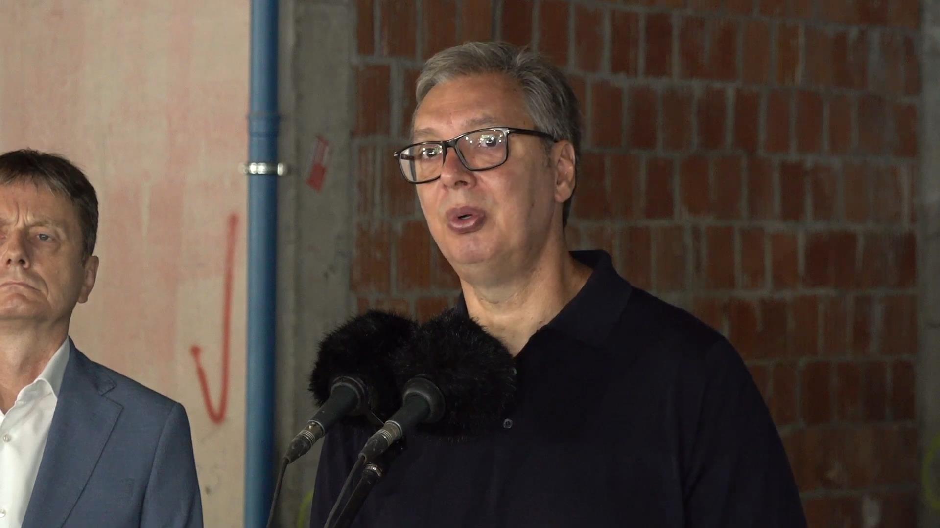 Predsednik Aleksandar Vučić govori za mikrofonima ispred zida od cigle na gradilištu