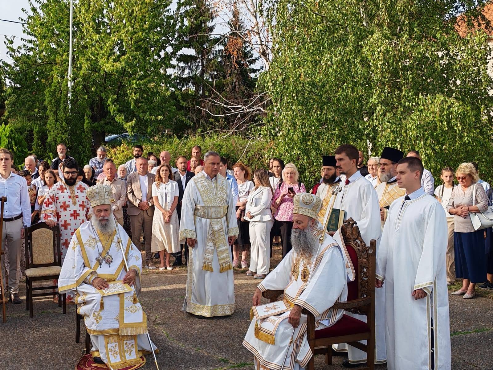 Patrijarh Porfirije i sveštenstvo u belim odeždama na liturgiji pod otvorenim nebom u Zucu, okupljeni građani u pozadini