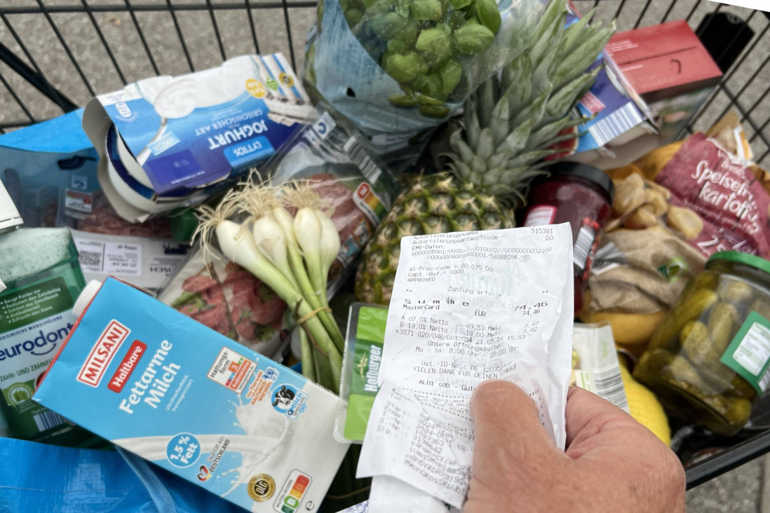 Kolica puna namirnica u prodavnici i ruka koja drži fiskalni račun
