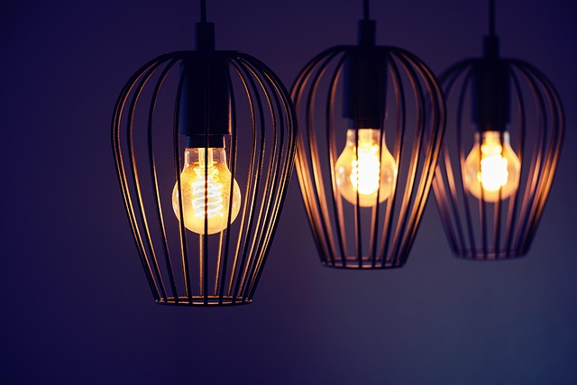 Tri viseće lampe sa žičanim abažurima i upaljenim sijalicama na tamnoplavoj pozadini