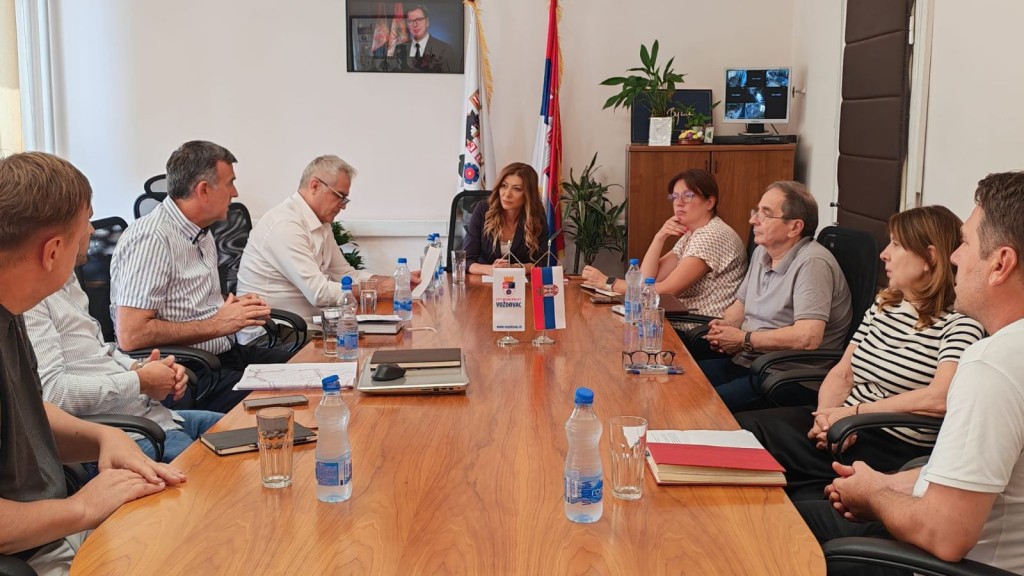 Radni sastanak za konferencijskim stolom u Opštini Voždovac, sa zastavicom opštine na sredini stola