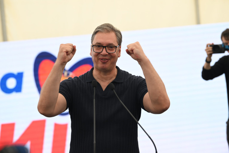 Aleksandar Vučić za govornicom, podignutih pesnica, ispred bine
