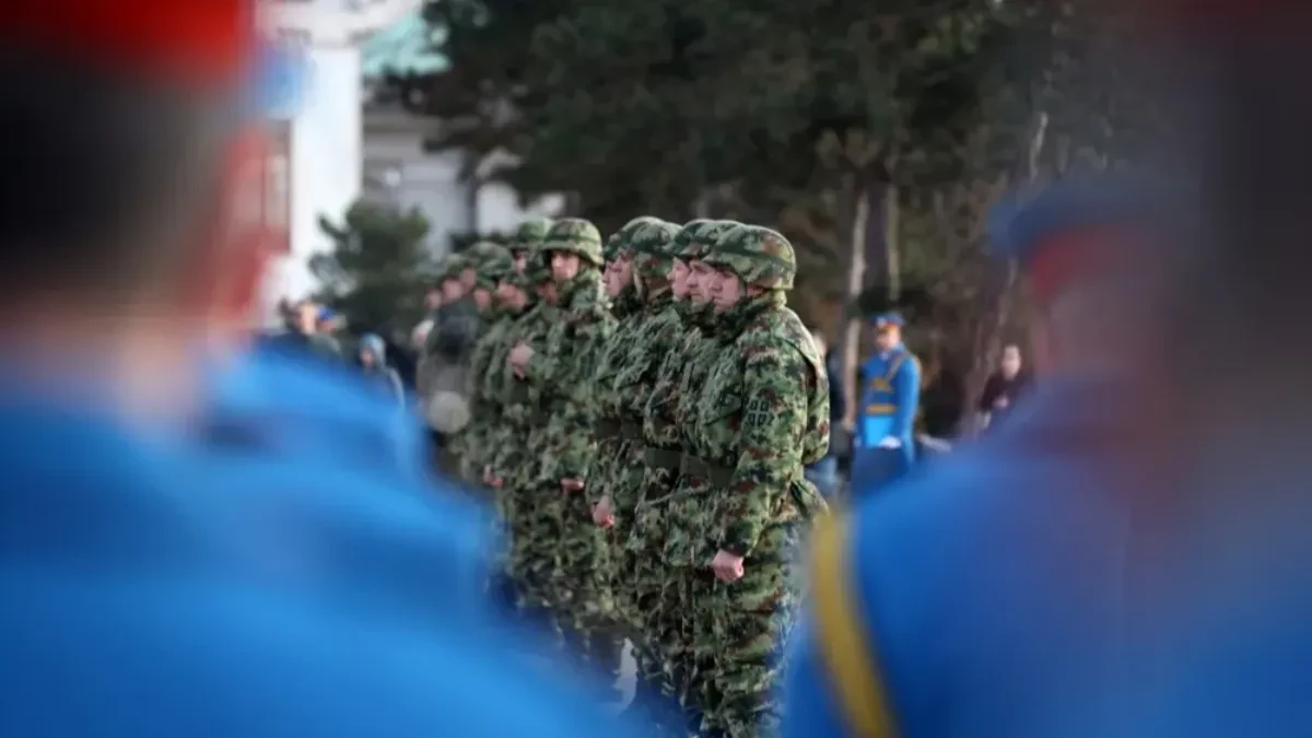 Postrojeni vojnici Vojske Srbije u maskirnim uniformama i šlemovima, u prvom planu zamućene plave uniforme garde