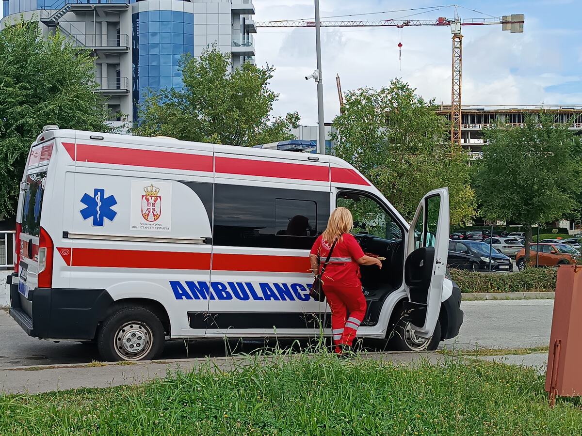 Vozilo Hitne pomoći i lekarka u crvenoj uniformi kod otvorenih vrata
