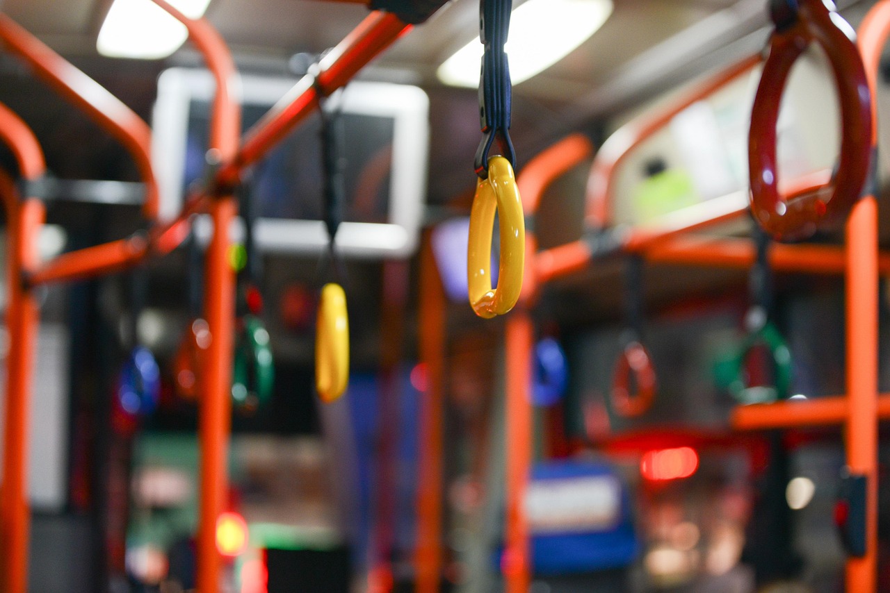 Unutrašnjost gradskog autobusa sa narandžastim rukohvatima i žutim visećim ručkama
