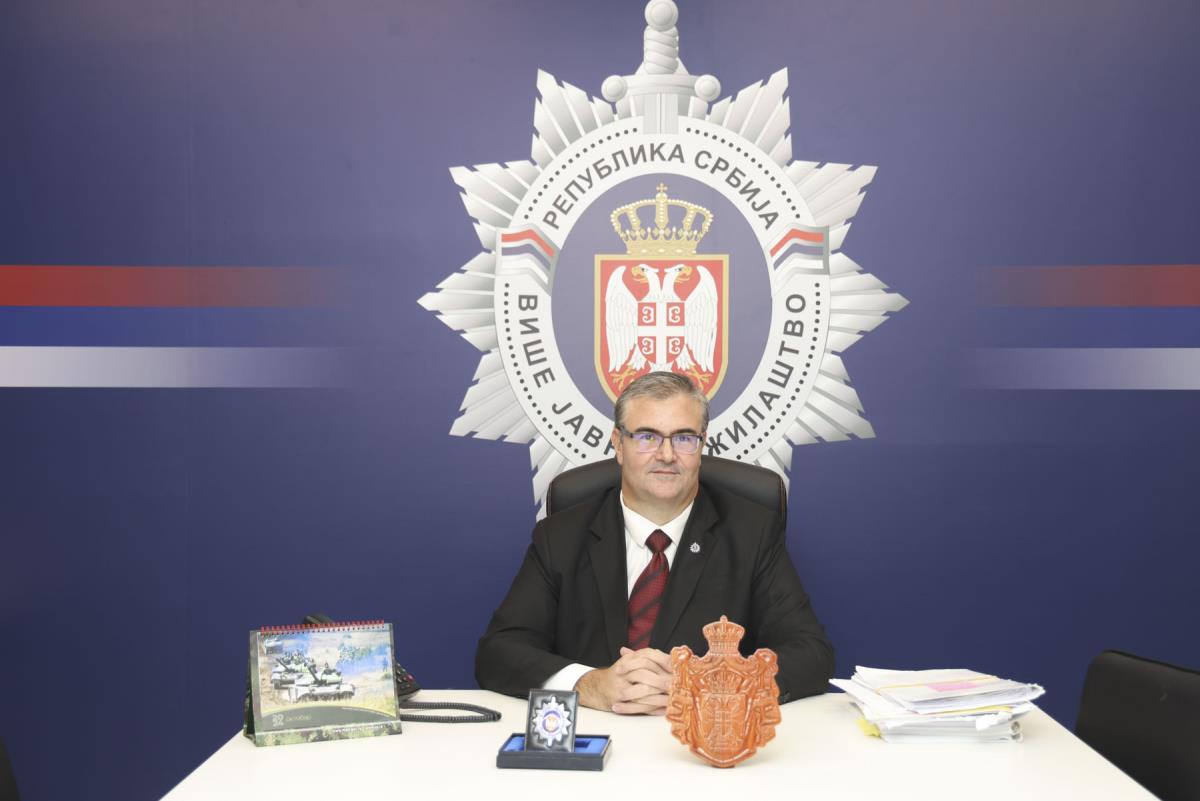 Muškarac u odelu sedi za stolom ispred grba Višeg javnog tužilaštva u Beogradu