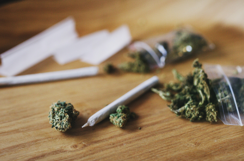 Osušena marihuana i smotane cigarete na drvenom stolu