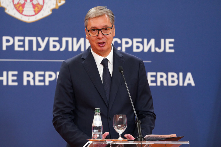 Aleksandar Vučić govori za govornicom ispred plave table sa natpisom Republika Srbija