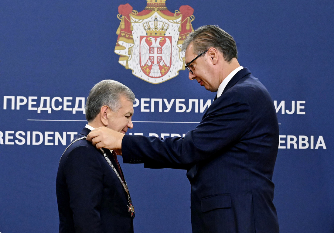 Aleksandar Vučić stavlja ordensku ogrlicu oko vrata Šavkata Mirzijojeva ispred grba Srbije