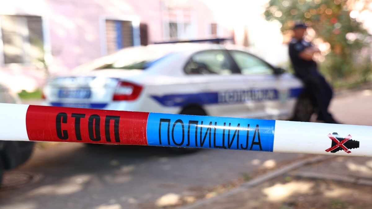 Policijska traka sa natpisom Stop policija, u pozadini policijski automobil i policajac