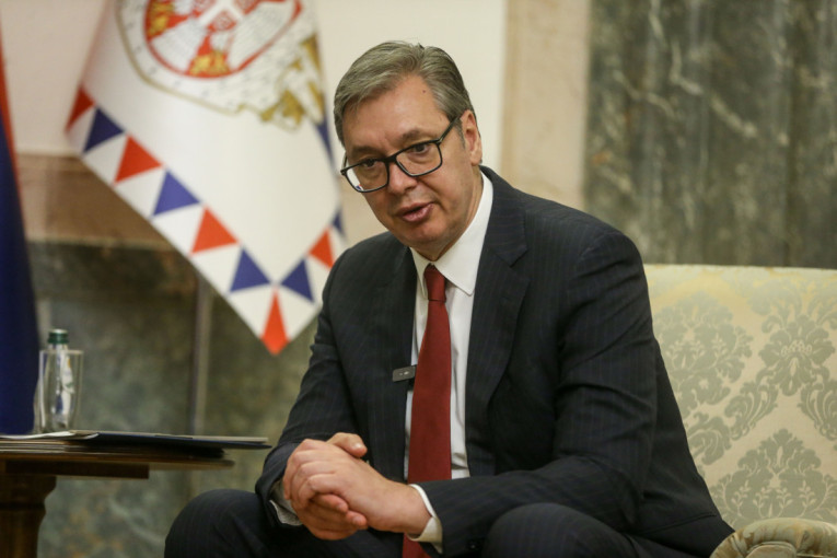 Aleksandar Vučić sedi u fotelji ispred zastave Srbije