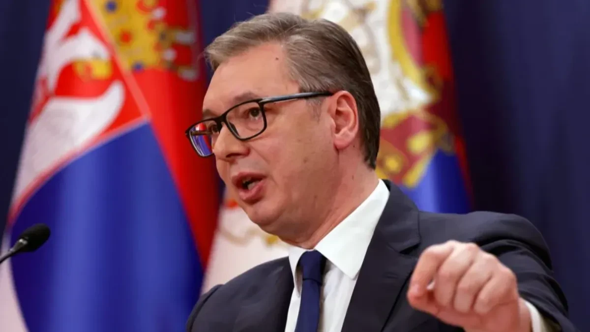 Aleksandar Vučić govori pred mikrofonom, iza njega zastave Srbije