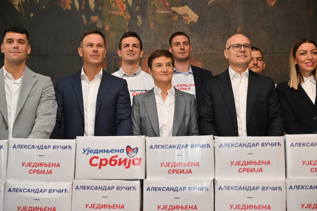 Predstavnici liste stoje iza naslaganih kutija sa natpisom „Aleksandar Vučić - Ujedinjena Srbija“
